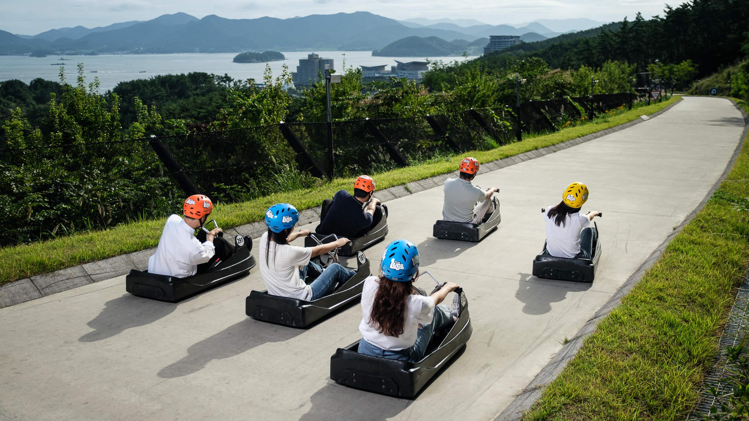 A group of people Luge down the track at Tongyeong.